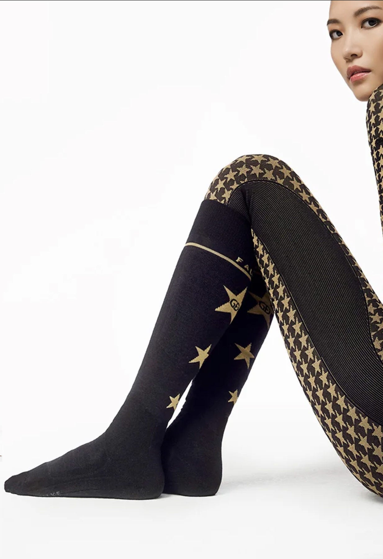 Goldbergh Black knee-high ski socks with gold star patterns and star print leggings on a white background